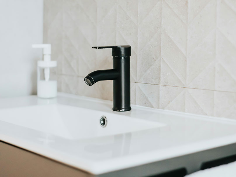 New black faucet installed on a white granite sink